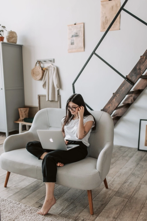 Girl Working on laptop sitting on Sofa, Image Showing Hassle-Free Household Shifting