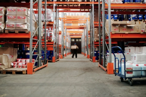 Man is arranging boxex in big Warehouse